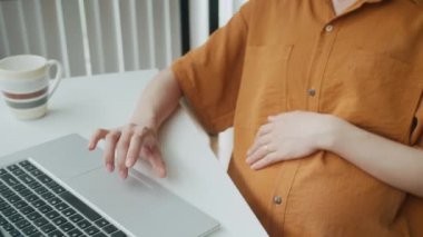 Müstakbel annenin migreni tutarken ofis masasındaki kablosuz laptoptan rapor verirken çekilen görüntüler.