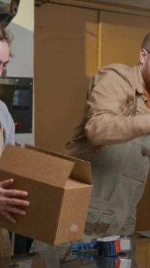 Meslektaşların kutular içinde taşınmak üzere taze kavrulmuş kahve tanelerini poşetlerine koyarken dikey çekimleri.