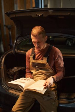 Araba servisinde çalışmadan önce araba motorunu inceleyen profesyonel bir tamirci.