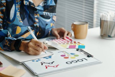 Proje üzerinde çalışırken, masa başında oturan, notlar yazan ve renkleri seçen tanınmayan kadın tasarımcıların orta boy yakın çekimi