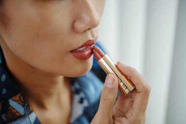 Genç Asyalı kadının sabahları hazırlanırken, rujunu sürerken, fotokopi çekerken.