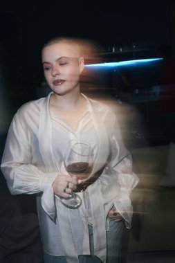 Zarif, güzel bir kadın ev partisine giderken kırmızı şarap içiyor.