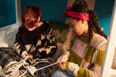 Yataktaki yatakta oturan iki yaratıcı Z jenerasyonunun yüksek açılı görüntüsü.