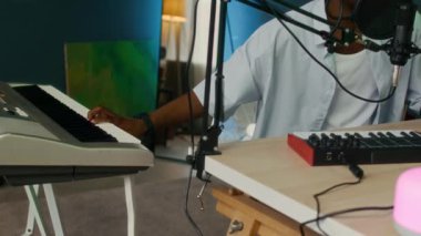 Afrika kökenli Amerikan gen Z uzmanının mikrofondaki sesi kaydederken ve ev stüdyosundaki akıllı müzik sistemini kullanırken çekilmiş el kamerası görüntüleri.