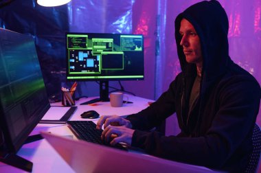 Karanlık ofiste bilgisayardaki kodlarla çalışan programcı