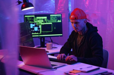 Programcı iş yerinde bilgisayarın önünde oturuyor ve karanlık ofisteki bilgisayarda yeni bir arayüz geliştiriyor