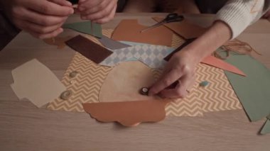 Evdeki masada otururken tanınmayan aile üyelerinin kağıt sanat projelerini yakından çekimleri.