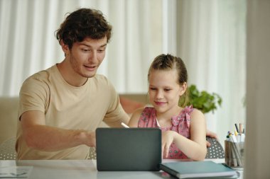 Liseli kız babasıyla birlikte internette çalışıyor.