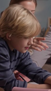 Kafkasyalı ebeveynlerin, oğullarına ev ödevlerini tartışırken yardım ederken çekilmiş dikey bir fotoğrafı.