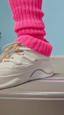 İç mekandaki aerobik platformda egzersiz yapan, bacak ısıtıcısı takan anonim sporcunun bacaklarının dikey çekimi.