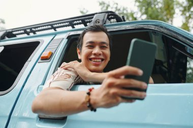 Arabayla seyahat ederken cep telefonuyla konuşan adam.