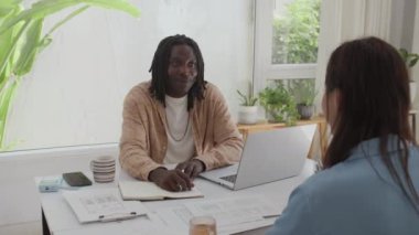 İki çok ırklı meslektaşın masa başında otururken projelerden bahsederken çekilmiş orta boy bir fotoğraf.