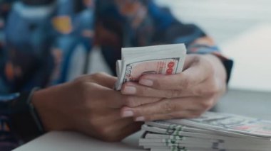 Kapalı mekanda çalışan ve elinde banknotları tutan isimsiz kadın memurun yakın çekimleri.