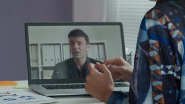 İş kadınının ofis masasında kablosuz bilgisayarın önünde otururken görüntülü konuşma görüntüsü.