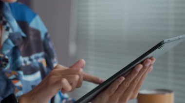 Ofiste çalışırken dijital tablette uygulamayı kontrol eden tanınamayan bir iş kadınının el kesimi.