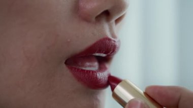 Güzellik ve zarafeti vurgularken dudaklarına koyu kırmızı ruj süren bir kadın.