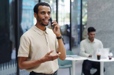 İşadamı ofiste çalışırken cep telefonuyla konuşuyor.
