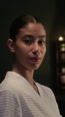 Beyaz bornoz giyen Z neslinin dikey göğüs üstü portresi güzellik muayenehanesinde kameraya poz veriyor.