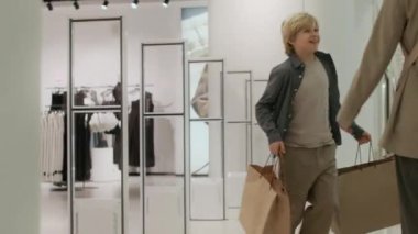 Kafkasyalı mutlu gencin alışveriş torbaları taşıması, annesiyle buluşması, alışveriş merkezindeki alışverişleri kontrol etmesi.