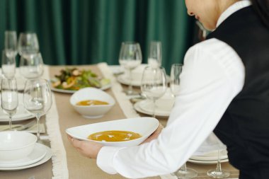 Garson yemek masasında sosları ve aperatifleri düzenlerken gülümsüyor.