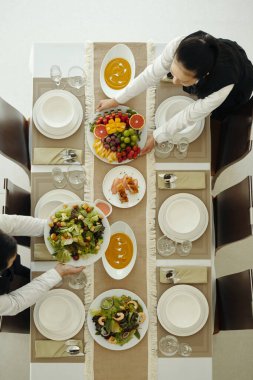 Yemek servisi sırasında yemek masasında servis edilen garsonların üst görüntüsü.