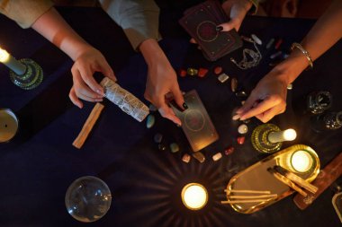 Yukarıdan bakıldığında tanınmayan üç kız fal bakıyorlar, tarot kartları ve sihirli nesneler kullanıyorlar.