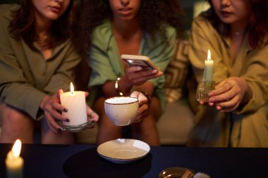 Sihirli parti sırasında kahve fincanında fal bakan üç farklı kız arkadaşın orta boy yakın çekimi.