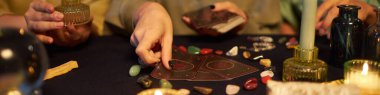 Masada oturan, küçük cadı partisi sırasında tarot kartları okuyan üç genç kadının orta ölçekli yakın çekimi.
