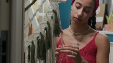 Yatakhanedeki pamuk ipliklerden örülmüş saç bandı ve örgü ören esmer Z genli kızın görüntüsünü aşağı eğ.