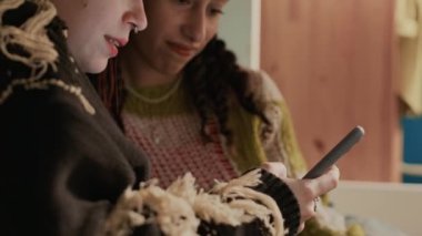 Yakın plan çekimde, akıllı telefondan sosyal medya içeriğini izleyen ve gülen iki Z jenerasyonu kız arkadaşının görüntüsü