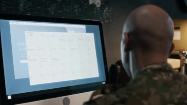 Siber güvenlik merkezinde bilgisayar üzerinde çalışırken hackleme saldırısını tespit eden erkek askeri ajanın arka görüntüsü