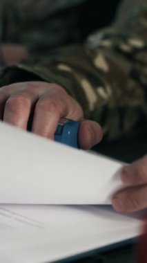 Komuta merkezindeki belgeleri inceleyen ve damgalayan isimsiz askeri ajanların dikey görüntüleri.
