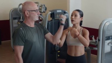 Genç bayan eğitmenin beden eğitimi dersinde rehabilitasyona uğrayan Kafkas sporcusuna rehberlik ettiği orta boy bir fotoğraf.