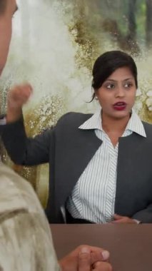 Dost canlısı Hintli kadın yöneticinin resepsiyonda erkek konukla konuşurken dikey çekimi.