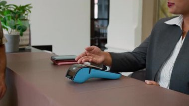 Kadın yöneticinin kablosuz terminalde kredi kartı ödemesini kabul ederken görüntüsü kesilmiş.
