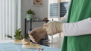 Klinikteki pitonun sağlığını incelemeye hazırlanırken tanınmayan veterinerlerin ellerinin koruyucu eldiven giymesi.