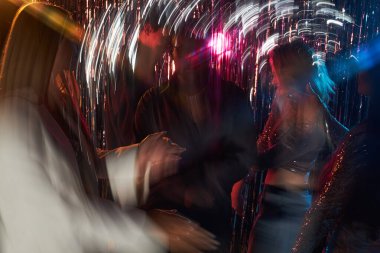 Göz kamaştırıcı ışıklar ve ışıltılı flamalar altında enerjik bir şekilde dans eden bir grup genç. Canlı atmosferli eğlence ve eğlence için popüler sosyal ortam