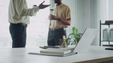 Ofisteki masadaki kablosuz bilgisayara odaklan. İki erkek girişimci arka planda bulanık kahve fincanlarıyla sohbet ediyor.