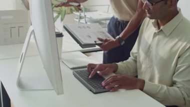 Ofisteki bilgisayarda çalışan iki adamın mali tabloları analiz ederken çekilmiş görüntüleri.