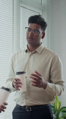 Ofisteki meslektaşımla kahve molası sırasında resmi giyinen erkek yöneticinin dikey görüntüsü.