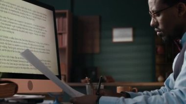 Erkek Afro-Amerikan editörün el kamerasıyla çekilmiş yeni senaryosu üzerinde çalışırken, masadaki kitap istisnaları hariç.