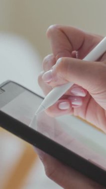 İsimsiz bir kadının tablet bilgisayarda yazı yazarken ya da resim çizerken çekilmiş dikey yakın plan görüntüleri.