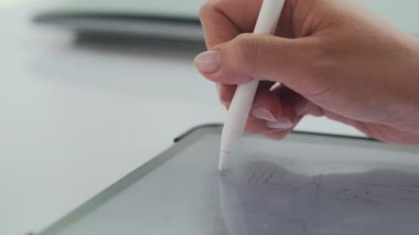 Tanımlanamayan kadın moda tasarımcısının masadaki tablet bilgisayarda çizim yaptığı makro resimler.