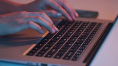 Neon 'da kablosuz dizüstü bilgisayarda çalışan isimsiz kadın kullanıcının ellerini yakın plan çek