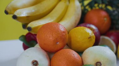 Sarı arka planda izole edilmiş portakal, elma, limon, mango, ananas gibi taze meyveleri yakından çek.