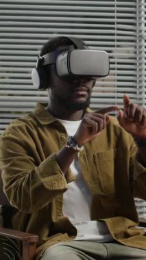 Sanal gerçeklik gözlüğü takan Afro-Amerikan bir erkeğin ofiste uygulamayı geliştirirken dikey çekimi.