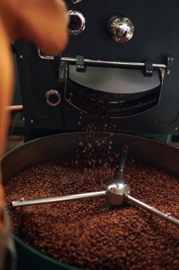 Fabrikadaki profesyonel kızartma makinesi tarafından kızartılan kahve çekirdeklerinin dikey çekimi.