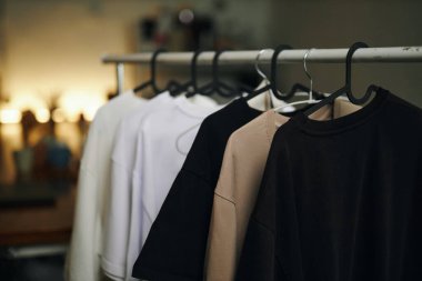 Orta büyüklükte pastel tişörtler ve siyah plastik askılar.