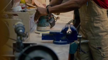 Afrika kökenli Amerikalı işçilerin atölyedeki masada tahta parlatmak için makine kullandıkları orta boy bir fotoğraf.