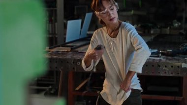 Çalıştıktan sonra kıyafetlerini talaştan temizleyen genç bir kadının orta boy fotoğrafı.